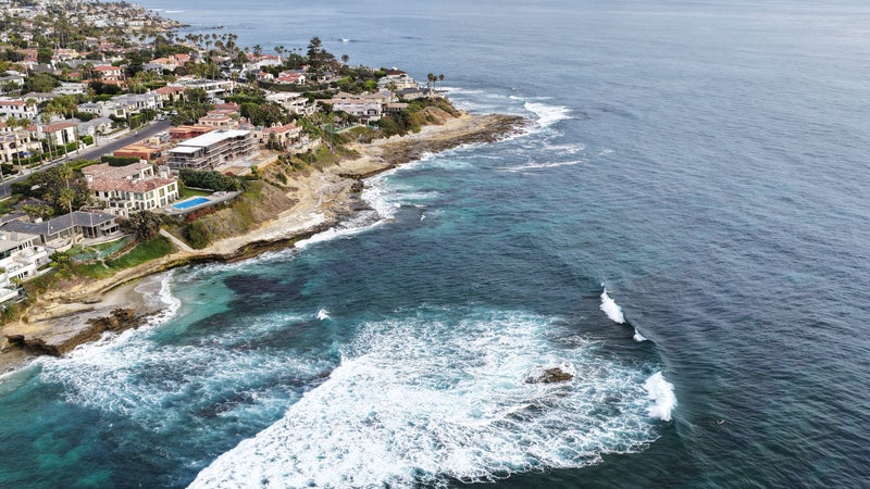 Les vagues de l’océan Pacifique viennent s’écraser près des maisons en bord de mer du quartier de La Jolla, le 13 août 2026 à San Diego, en Californie