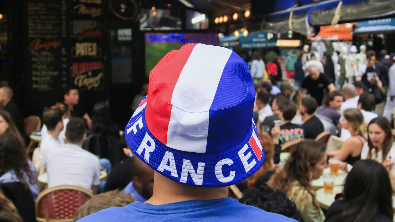 France supporters in national colors watching a World Cup match from a bar terrace.